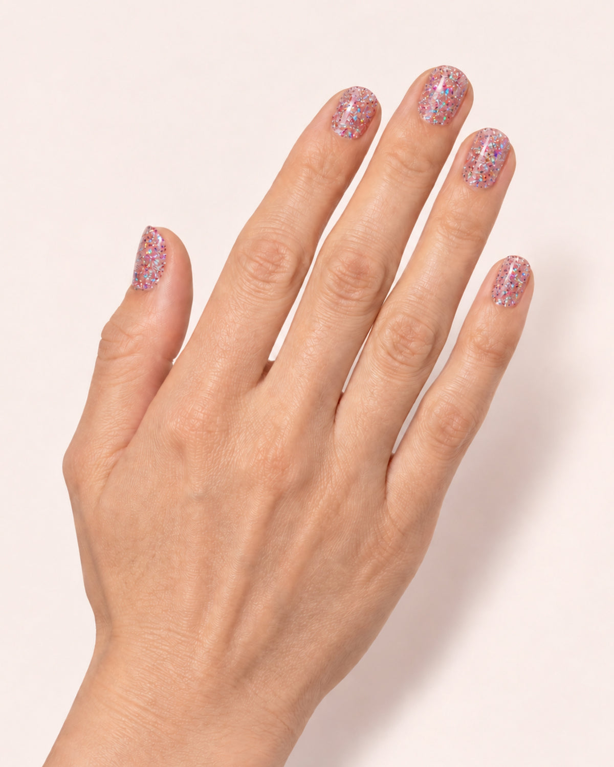 Mayvee nail polish in 'Cancel My Plans' pink holographic glitter nail colour on fair skin tone