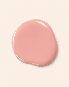 A glossy, irregular-shaped smear of dusty pink nail polish on a solid off-white background.